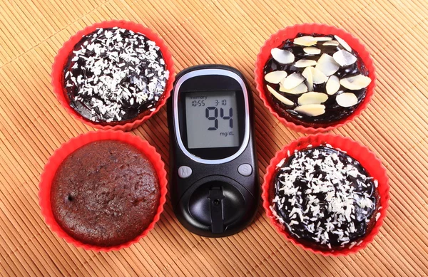 Medidor de glucosa y magdalenas de chocolate en tazas rojas — Foto de Stock