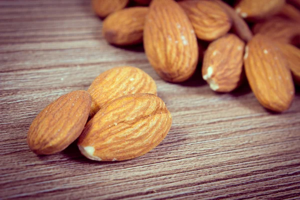 Vintage photo, Heap of almonds on wooden background — Zdjęcie stockowe