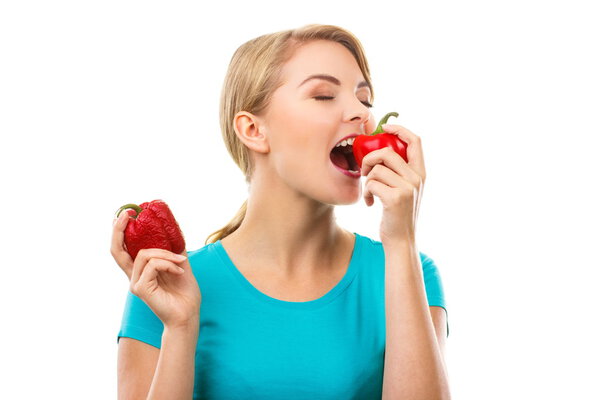 Woman holding wrinkled peppers and eating fresh ripe peppers, white background