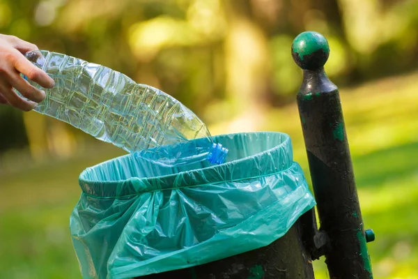 Main de femme jetant bouteille en plastique dans la poubelle de recyclage, la litière de l'environnement — Photo