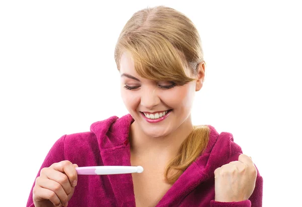 Щаслива жінка дивиться на тест на вагітність з позитивним результатом — стокове фото
