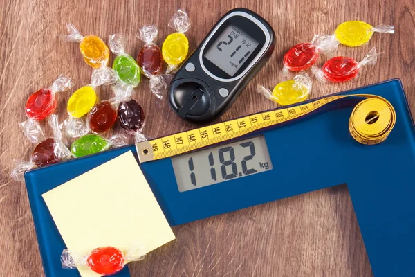 Elektronische weegschaal en glucometer met resultaat van de meting en kleurrijke snoepjes, diabetes, vermagering en vermindering van het eten van snoep — Stockfoto