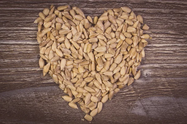 Vintage photo, Heart of sunflower seeds on wooden background — Stock Photo, Image