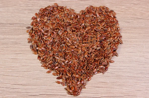 Heart of linseed on wooden background — Stock Photo, Image