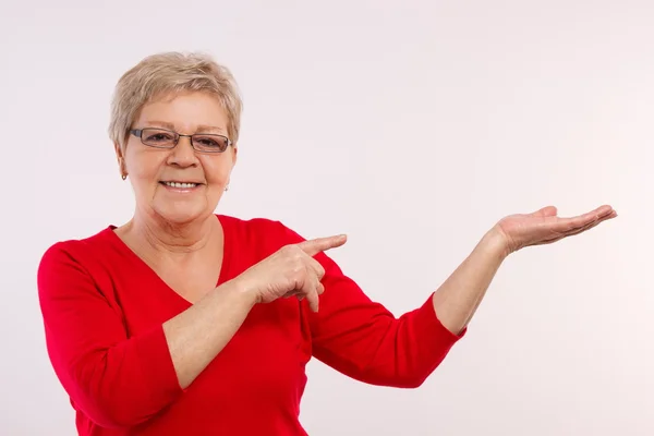 Felice donna anziana sorridente mostrando la mano vuota, copiare lo spazio per il testo — Foto Stock