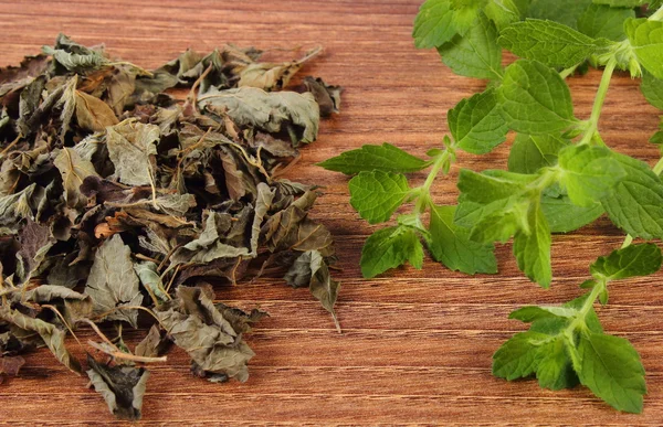 Fresh and heap of dried lemon balm on wooden table, herbalism — Stock Photo, Image