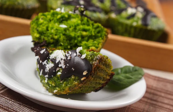 Fresh muffins with spinach, desiccated coconut and chocolate glaze, delicious healthy dessert — Stock Photo, Image