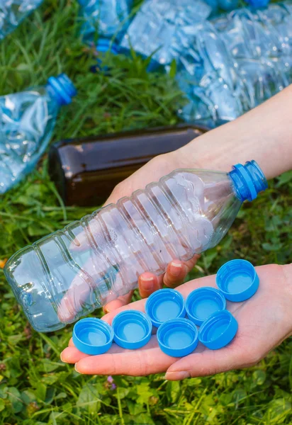Main de femme avec bouteille en plastique et bouchons de bouteille, la litière de l'environnement — Photo