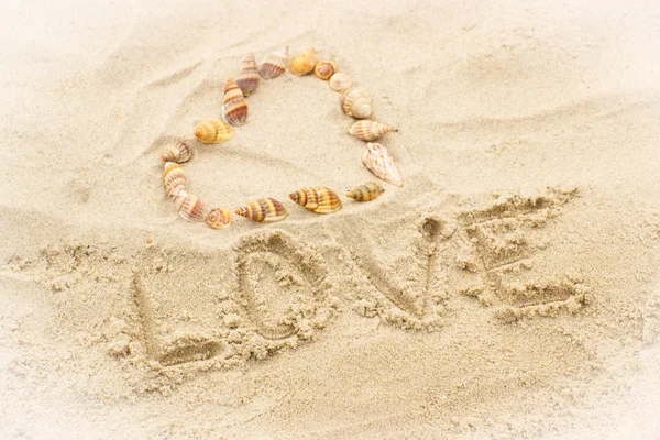 Word love written on sand at the beach, heart of shells Royalty Free Stock Images