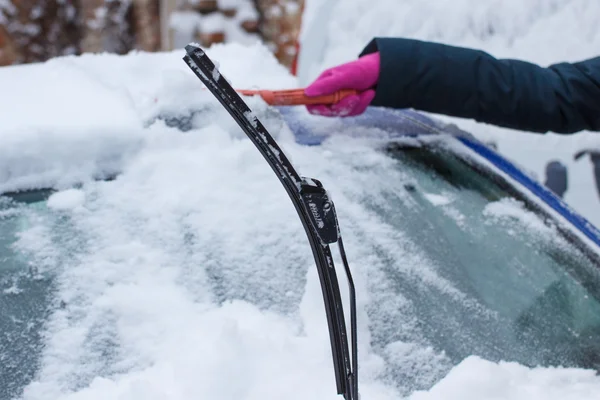 Hand van vrouw met behulp van de borstel en verwijdert sneeuw van auto en voorruit — Stockfoto