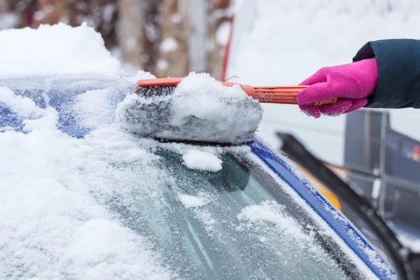 Mano della donna con pennello e rimuovere la neve da auto e parabrezza — Foto Stock