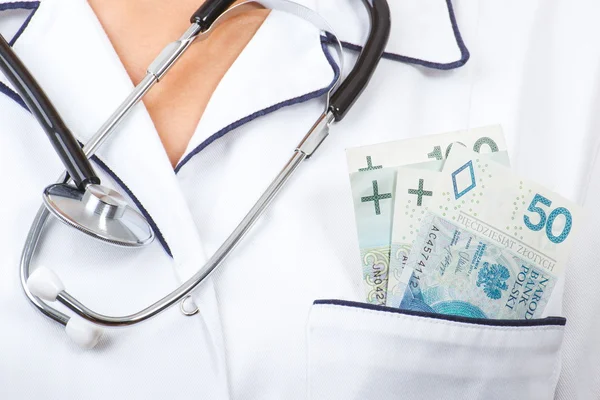Woman doctor with stethoscope and polish currency money in apron pocket, corruption, bribe or paying for care concept — Stockfoto