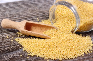 Darı, kabuğu çıkarılmış tane cam kavanozdan dökülmesini. Ahşap arka plan