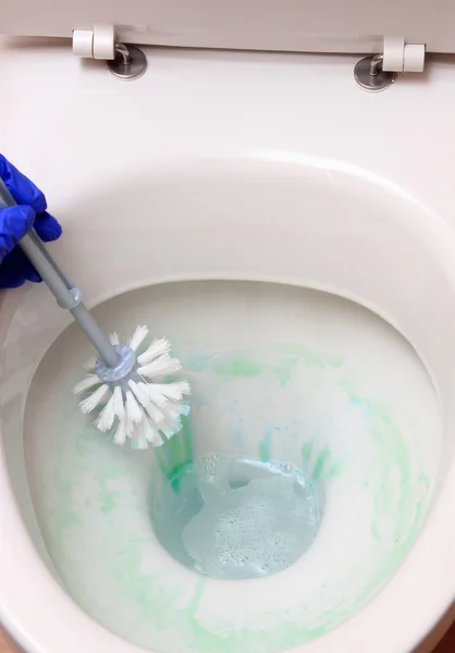 Main de femme en gant bleu nettoyage cuvette de toilette — Photo