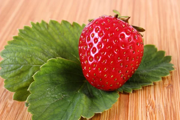 Strawberry with leaves on wooden surface — Stock Photo, Image