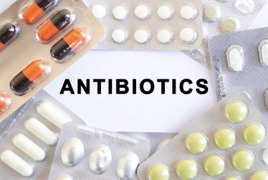 Beyaz arkaplandaki AntiBIOTICS mesajını gönder. Etrafta farklı ilaçlar var. Tıbbi konsept.