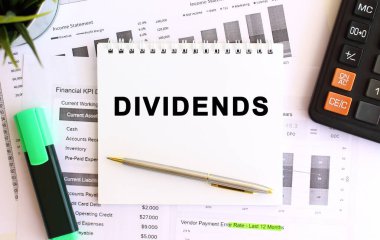 Hesap makinesi ve ofis malzemelerinin yanında beyaz bir arkaplan üzerinde SMS DIVIDENDS olan bir not. İş konsepti.