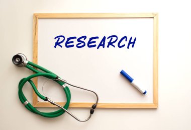 Beyaz tahta üzerinde steteskop var ve kelime yazılı..