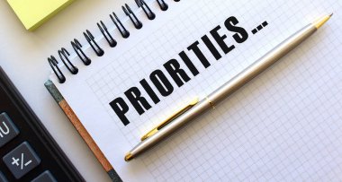 Not defterinin yanında hesap makinesi ve sarı not kağıtları yer almaktadır. İş konsepti.