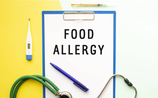 Text FOOD ALLERGY on a letterhead in a medical folder. Stethoscope, thermometer on a colorful background.