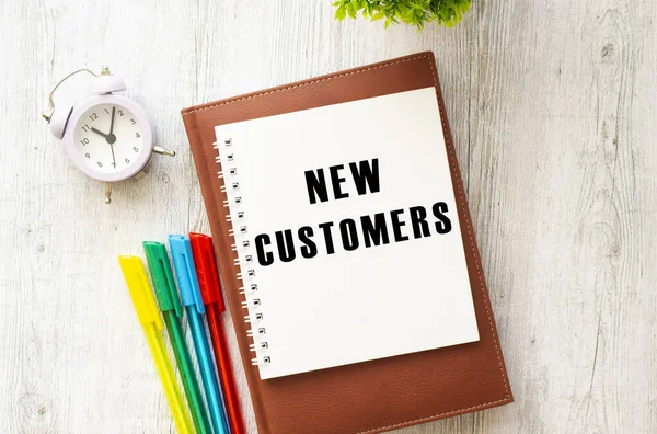Brown Notepad Inscription New Customers Colored Pens Clock Wooden Background — Stock Photo, Image