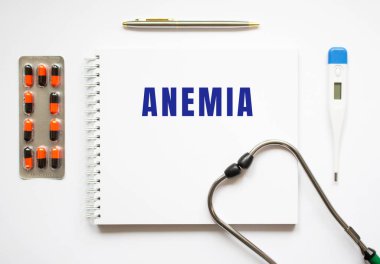 Masa ve steteskop üzerinde duran bir deftere yazılmış ANEMIA metni. Tıbbi konsept.