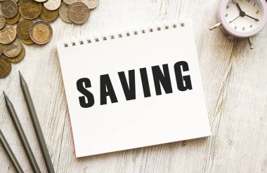 Not defterine mesaj kaydetmek gibi. Bozuk paralar dağınık, kalemler gri ahşap arka planda. Mali konsept.