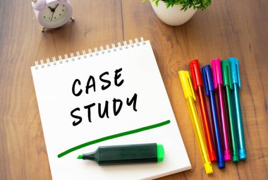 Bir yay üzerinde beyaz bir çarşaf üzerinde CASE STUDY yazılı bir defter renkli kalemlerle kahverengi bir ahşap masada yatıyor. İş konsepti.