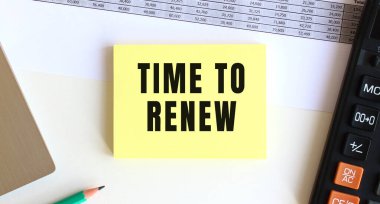 Bilgisayarın, hesap makinesinin ve ofis malzemelerinin yanında Time to ReNEW 'in olduğu metni not et. İş konsepti.