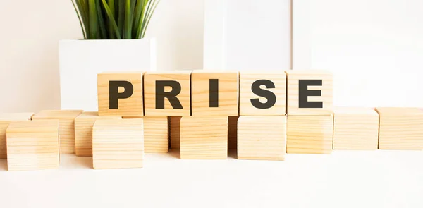 Wooden cubes with letters on a white table. The word is PRISE. White background. — Stock Photo, Image