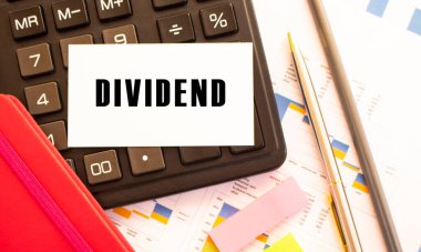 Metal kalem, hesap makinesi ve finansal tablolarla birlikte beyaz karta ayrık mesaj at. İş ve mali konsept