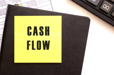 Masaüstünüzdeki bir etiket üzerindeki CASH FLOW metni. Günlük ve hesap makinesi. Mali konsept.
