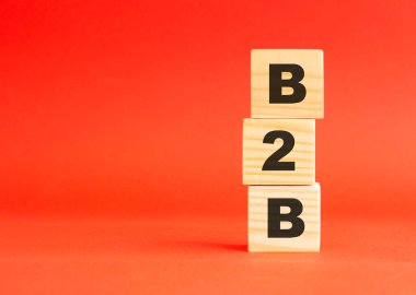 Tahta küplerde B2B yazıyor. Tasarım ve konseptin için. Kırmızı arka planda tahta küpler. Solda boş alan.