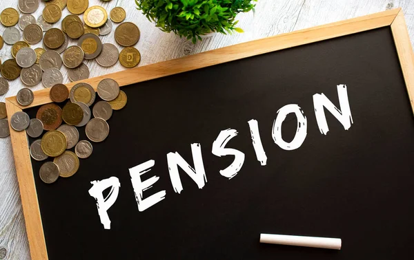 Üzerinde PENSION yazılı karatahta ve gri ahşap bir masada metal paralar. Mali konsept.