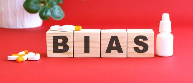 BIAS kelimesi kırmızı arka planda tıbbi ilaçlarla birlikte tahta küplerden yapılmıştır..