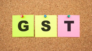 Mantar panoya yapıştırılmış çok renkli notlar. Kelime GST. Çalışma alanı.