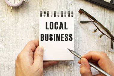 El, LOCAL BUSINESS metnini kurşun kalemle bir deftere yazar. Yukarıdan bak. İş konsepti.