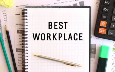 Ofis masasında, hesap makinesi ve ofis malzemelerinin yanında en iyi çalışma yeri yazılı not defteri..