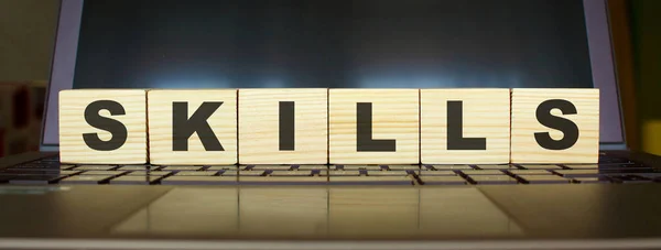 Word SKILLS. Wooden cubes with letters isolated on a laptop keyboard. Business Concept image.