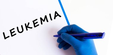 Tıbbi eldivendeki kadın doktorun eli bir belgede LEUKEMIA yazısını oluşturur. Tıbbi konsept.