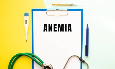 Çok güzel bir arka planda, tıbbi bir klasördeki antette ANEMIA metni var. Stetoskop, termometre ve kalem..