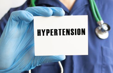 Doktor HYPERTENSION yazılı bir kart tutuyor..