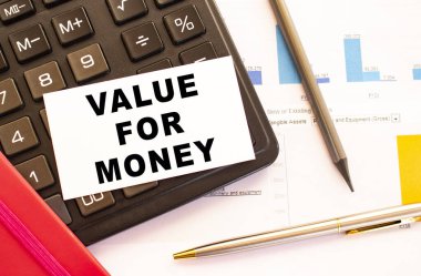Metal kalem, hesap makinesi ve finansal tabloları olan beyaz kart üzerinden para için VALUE 'ya mesaj at. İş ve mali konsept