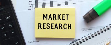 MARKEN REARCH 'ı ofis masasındaki mali tabloların üzerinde duran bir not defterinin sayfasına mesaj at. Hesap makinesinin yanında. İş konsepti.