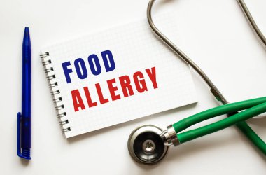 FOOD ALLERJİ, kalem ve steteskopun yanındaki beyaz bir masada bir deftere yazılır. Tıbbi konsept