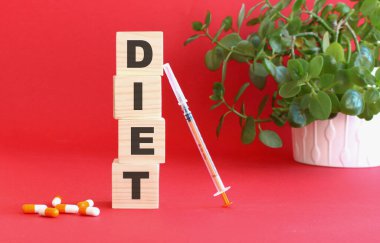 Diyet kelimesi kırmızı arka planda tıbbi ilaçlı tahta küplerden yapılmıştır..