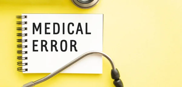 Text MEDICAL ERROR on notebook with stethoscope on yellow background. Medical concept.
