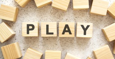 PLAY kelimesi, üzerinde harfler olan ahşap küplerden oluşur, arka planda üst görünüm. Çalışma alanı.