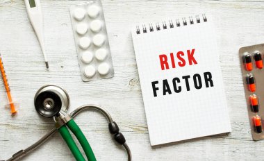 RISK FACTOR, ilaç ve steteskopun yanındaki beyaz bir masanın üzerindeki bir deftere yazılır. Tıbbi konsept
