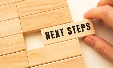 Elinizde, içinde NEXT STEPS yazan ahşap bir küp var. Pozitif düşünce konsepti